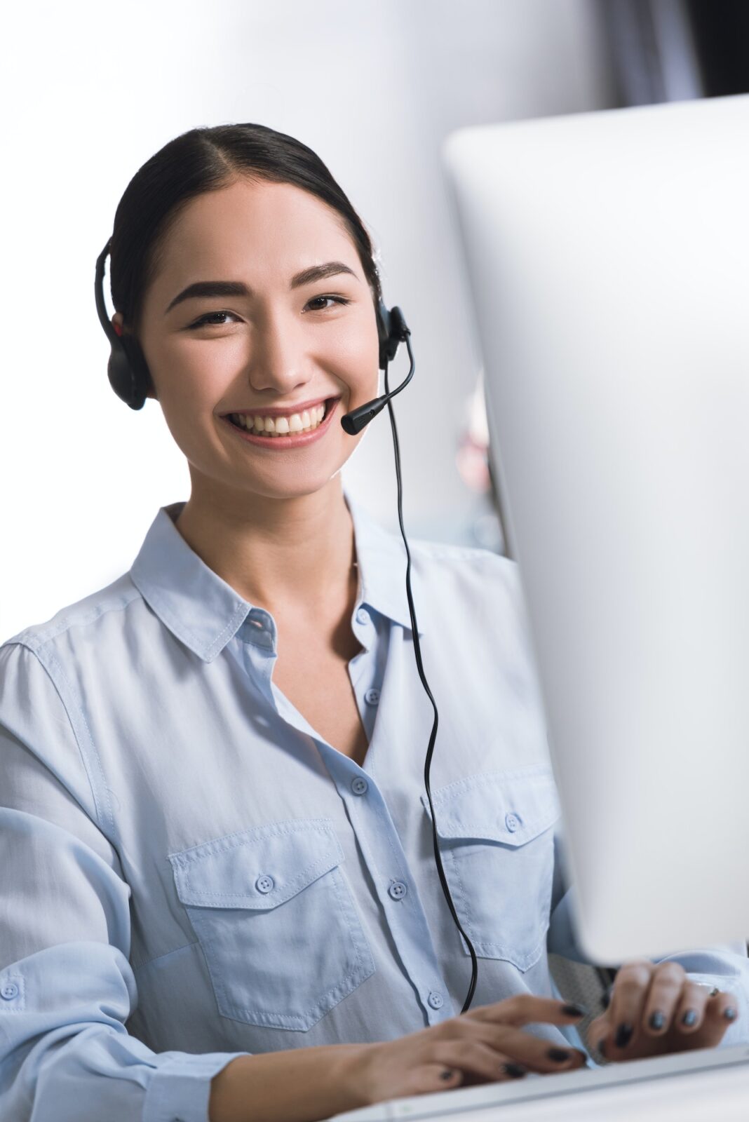portrait of smiling asian call center operator in headset looking at camera