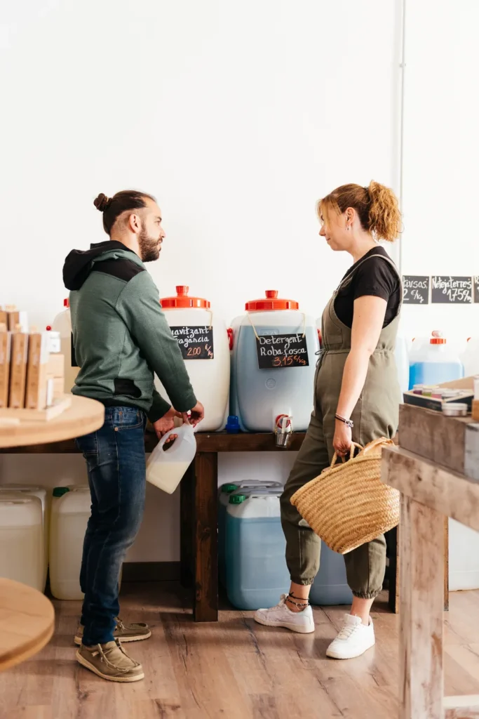 Dos miembros de un restaurante embotellan químicos de varios galones como parte de la venta de productos de limpieza industrial.